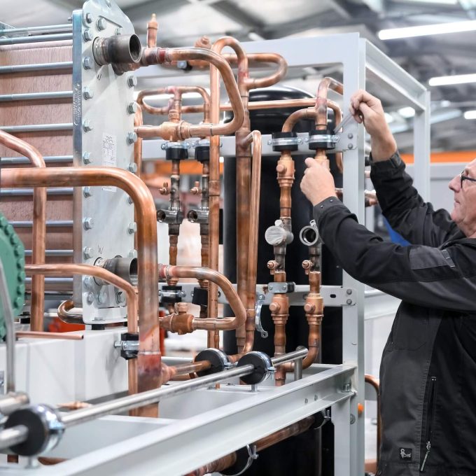 Happy refrigeration factory worker, assembling a CO2 Refrigeration rack at Refra factory in Lithuania