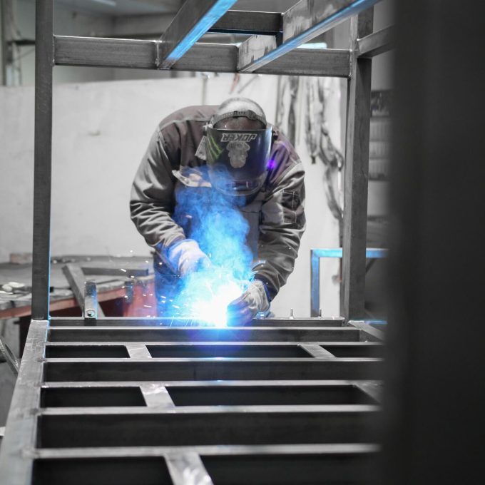 Refrigeration factory worker, welding a frame for Refra cooling equipment